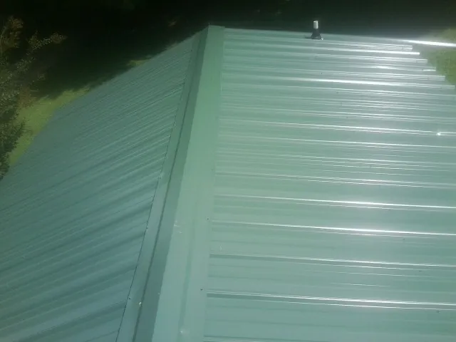 New green metal panels meeting at the ridge of a roof in La Grange
