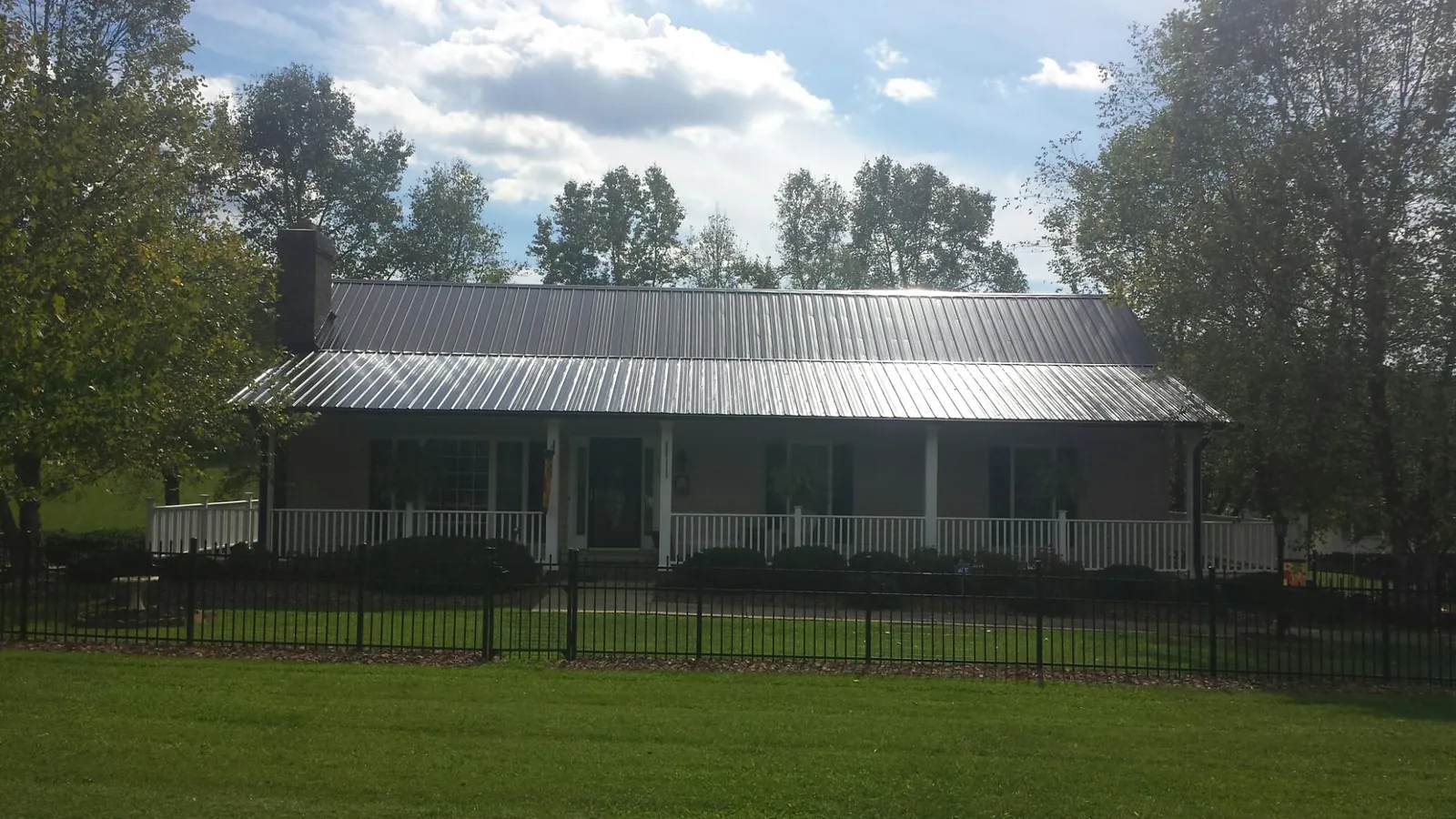 Gray metal roof on a brick ranch with a full width front porch — Gutter Guard Installation work by our crew in La Grange
